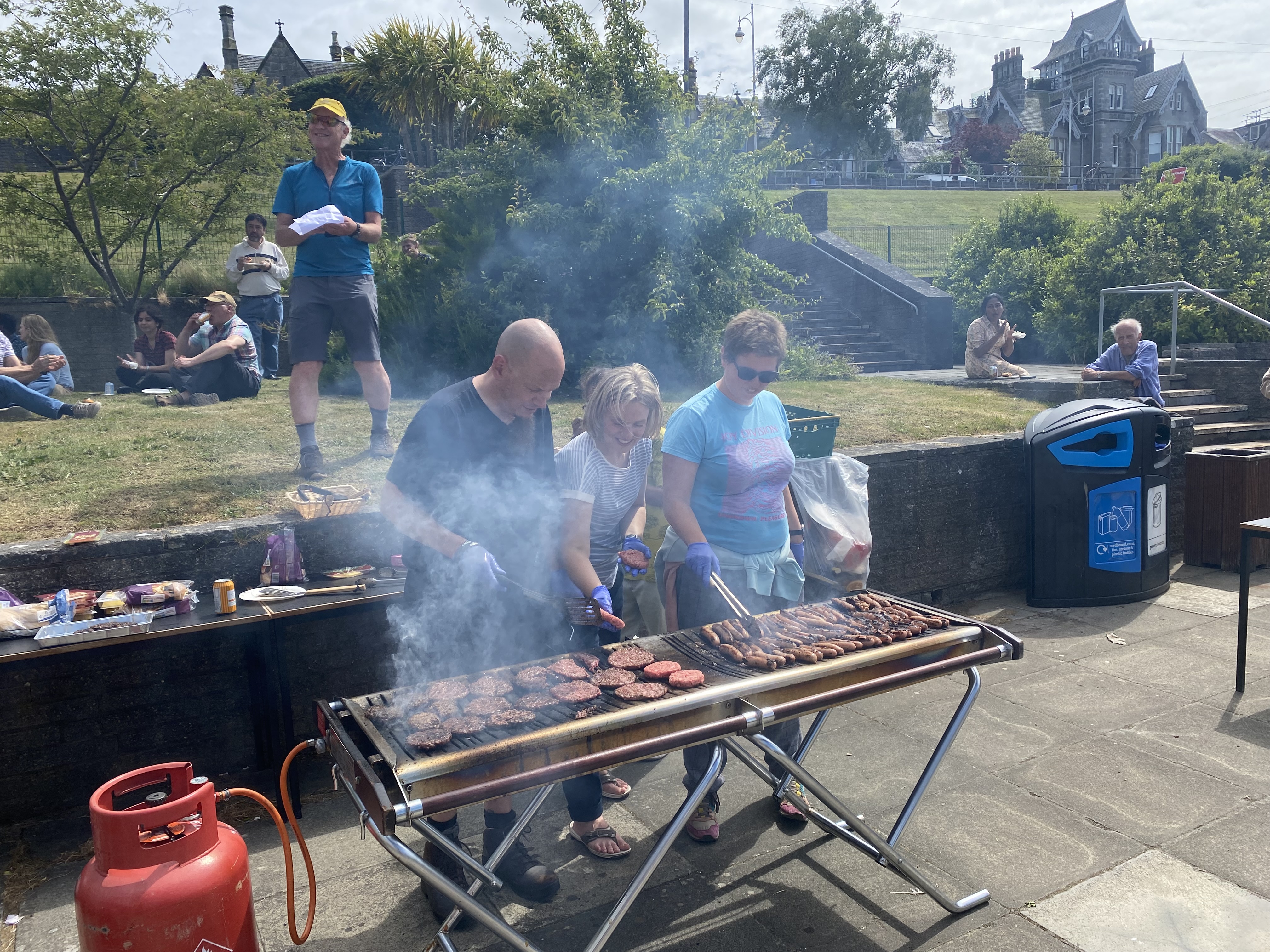 The barbecue in the sunshine, Dr Paul Cruickshank, Dr Lucy Hadfield and Janet with Professor Ian Bonnell making a speech in the background